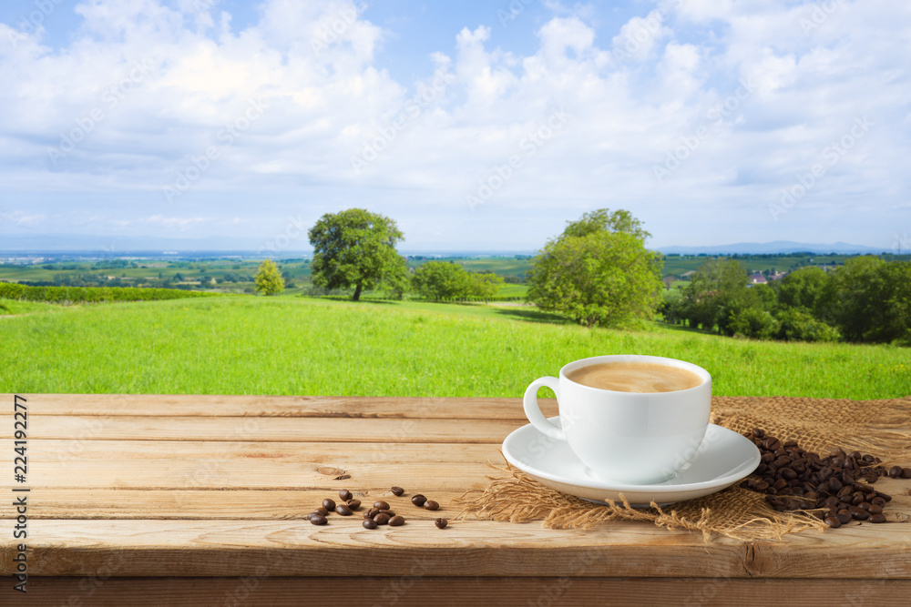 Coffee cup on wooden table over beautiful landscape background