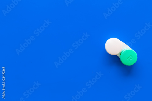 Improve vision concept. Contact lenses in container on blue background top view copy space photo