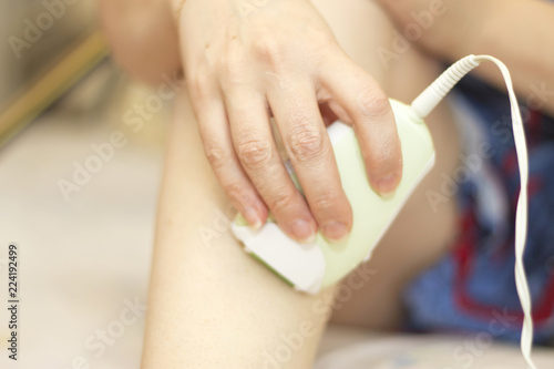 Female make a legs depilation by using a hair removal device