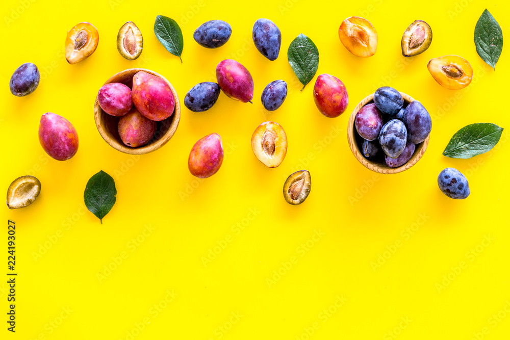 Bright fruitty background. Plum pattern. Red and purple plum and leaves on yellow background top view copy space