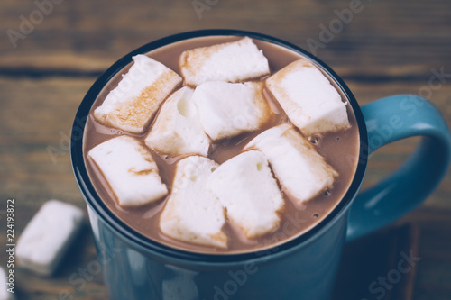 Cup of hot cocoa or hot chocolate with marshmallows and cinnamon sticks on wooden background. Winter mood. Close up.