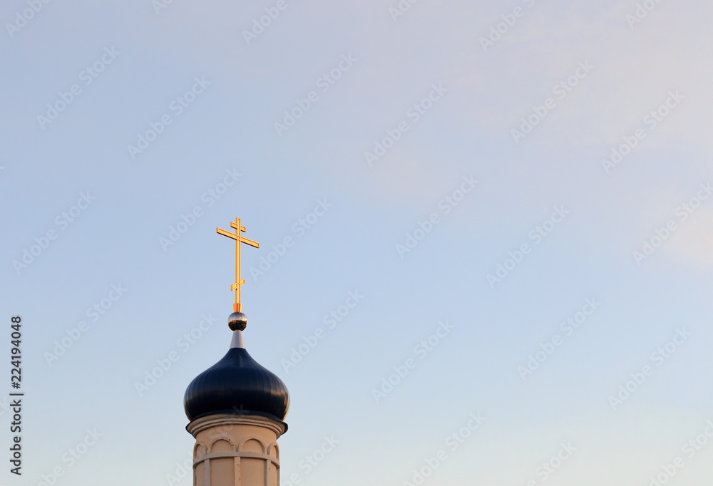 The orchard of the Orthodox Church with a golden cross against the sky