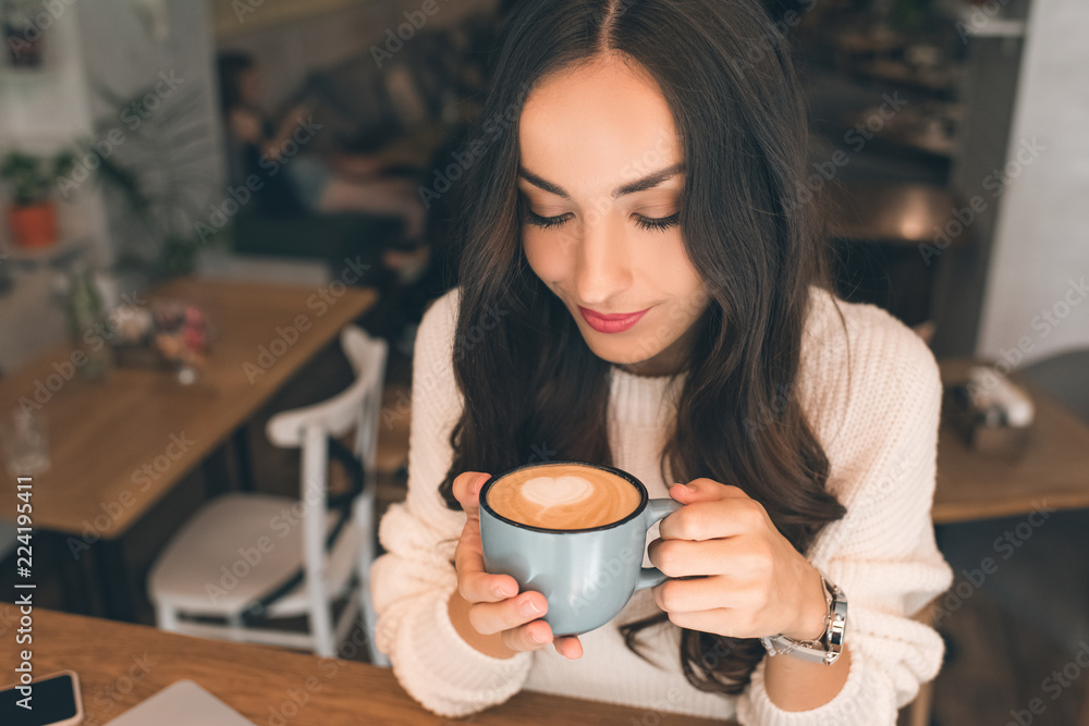 high angle view of young attractive woman drinking coffee at table in cafe high angle view of young attractive woman drinking coffee at table in cafe