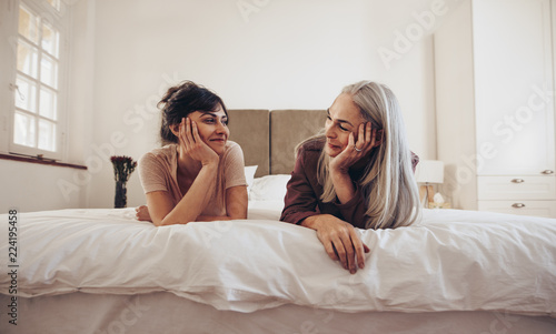 Happy mother and daughter talking while resting on bed photo