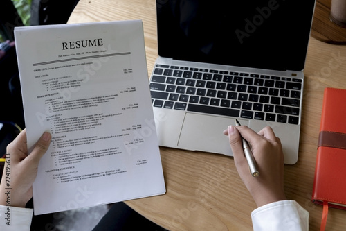 Business man review his resume application on desk, laptop computer, job seeker