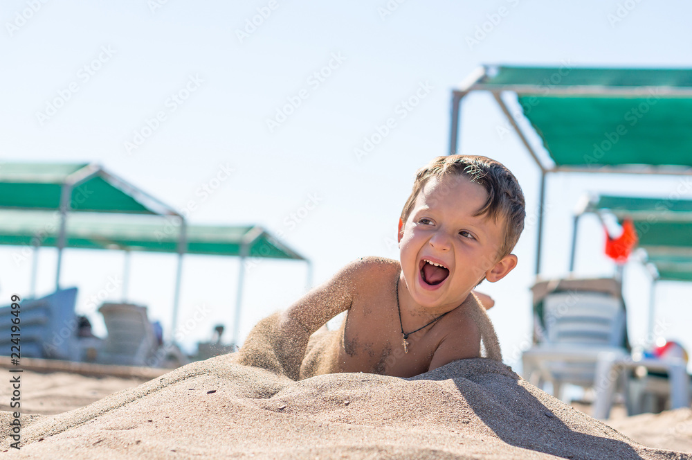 Smiling little baby boy sitting and playing with the sand. Positive human emotions, feelings, joy.