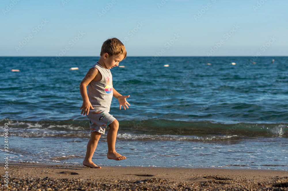 Smiling little baby boy playing in the sea. Positive human emotions, feelings, joy.