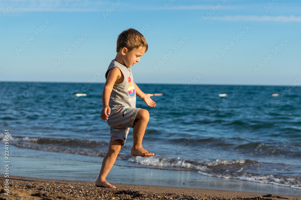 Smiling little baby boy playing in the sea. Positive human emotions, feelings, joy.
