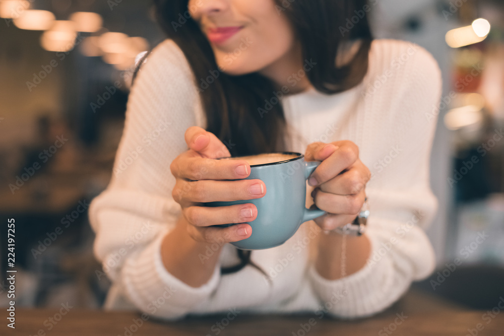 partial view of woman holding coffee cup at table in cafe partial view of woman holding coffee cup at table in cafe