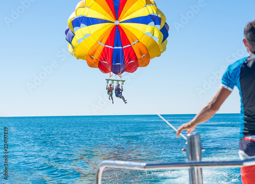 Happy couple Parasailing in Dominicana beach in summer. Couple under parachute hanging mid air. Having fun. Tropical Paradise. Positive human emotions, feelings, family, children, travel, vacation.  photo