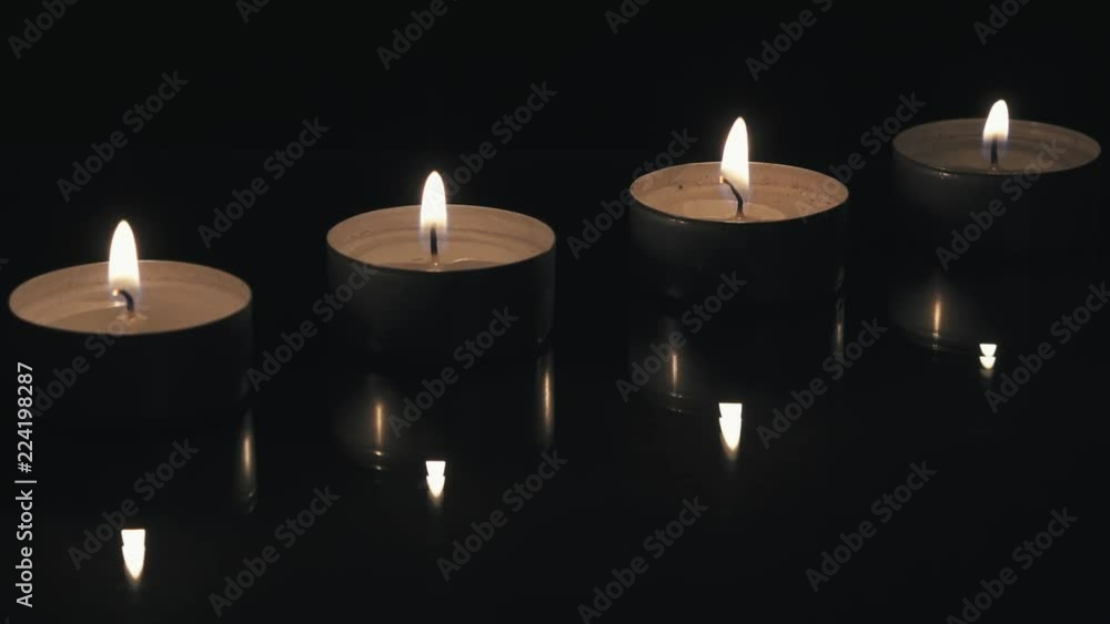 Lighted small candles with reflections in a dark background Lighted small candles with reflections in a dark background