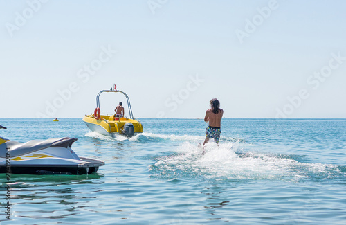 Young man glides on water skiing on the waves on the sea, ocean. Healthy lifestyle. Positive human emotions, feelings, joy.