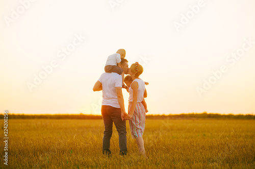 Young family at sunset kissing, family mother father and boys