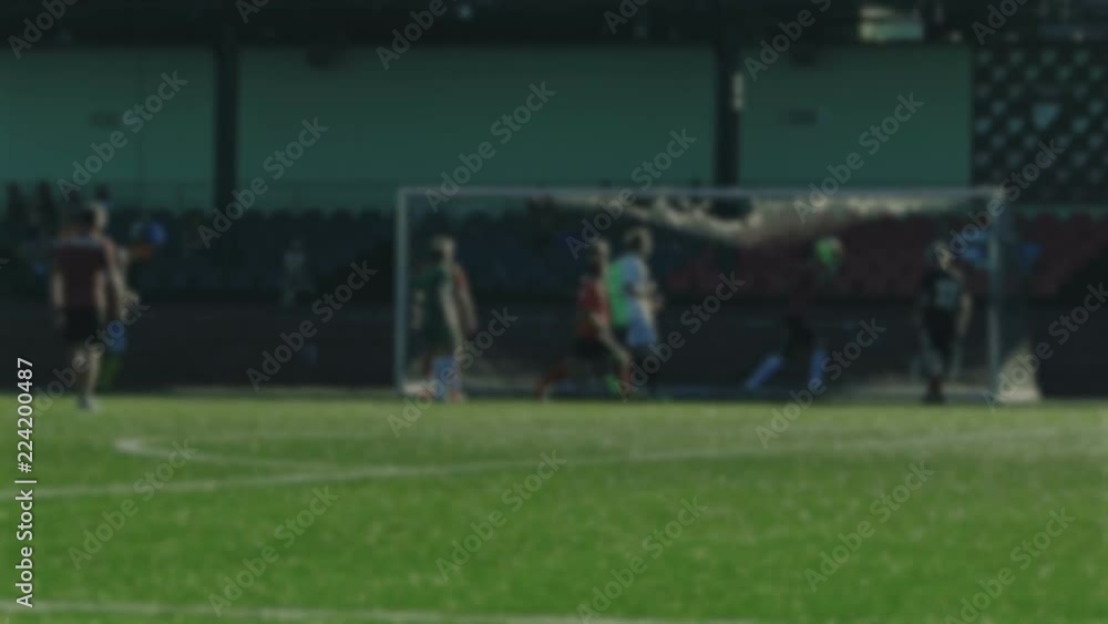 Goalkeeper catches a ball by hands and save a net during soccer game, football player attacks, blurred for background Goalkeeper catches a ball by hands and save a net during soccer game, football player attacks, blurred for background