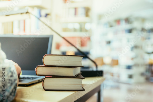 Studentin arbeitet in Bibliothek, Bücher und Laptop, Bücher im Hintergrund photo
