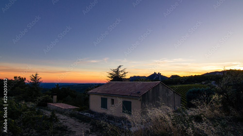Farm house with the Dentelles de Montmirail in the distance during sunset in Vaucluse, Provence, France Farm house with the Dentelles de Montmirail in the distance during sunset in Vaucluse, Provence, France