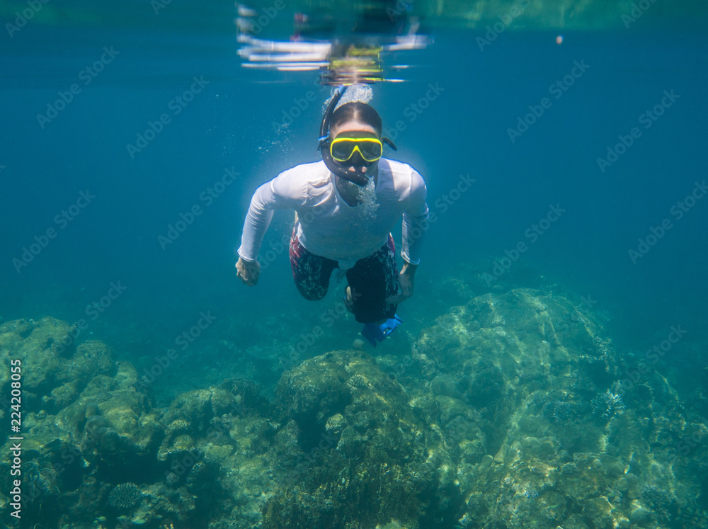 Underwater shoot of a young man in white shirt snorkeling in a tropical sea. vacation concept