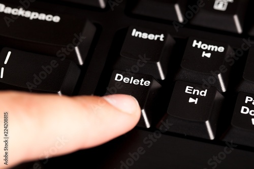 Finger Pressing the Delete Key on a Keyboard