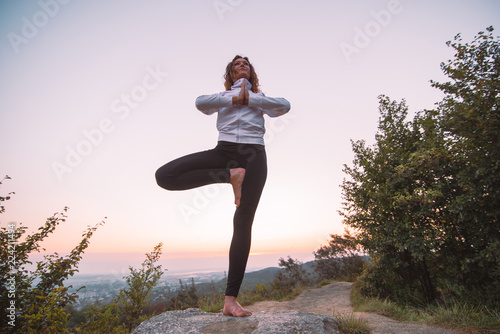 woman do yoga exercises at top of the hill on sunrise