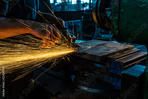 The worker polishes the metal with a grinding machine and sparks close-up.