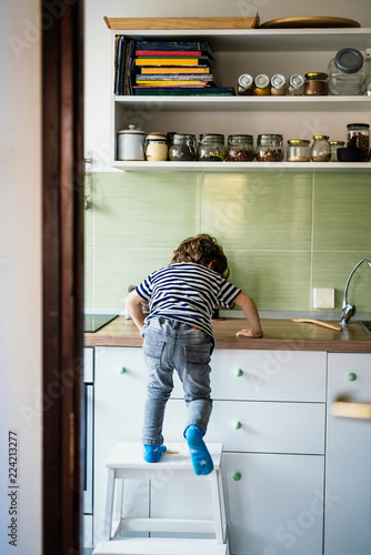 Little boy climbing on a countertop in his kitchen