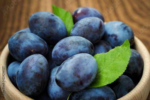 Fresh blue plums on wood table background. Sweet autumn fruit. Delicious and healthy raw food full of vitamins.