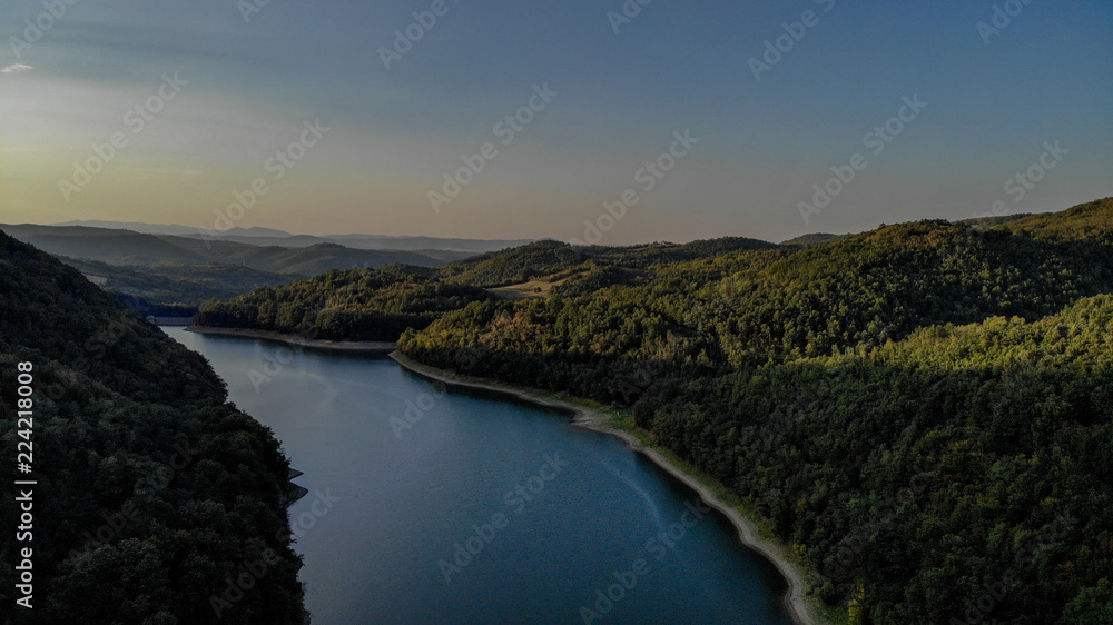 Obraz premium Aerial view, sunset in first day of autumn, green and yellow leaves on trees - lake Vodojaza near the Kragujevac