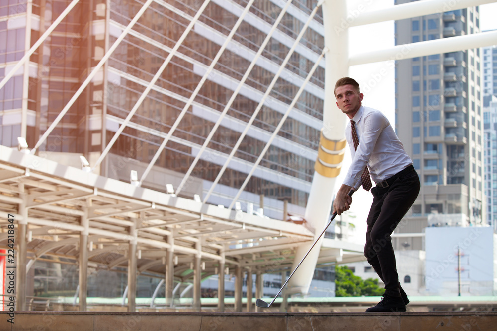 Fototapeta premium Businessman playing golf with cityscape on the background