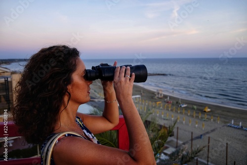 girl looks at the sea with binoculars
