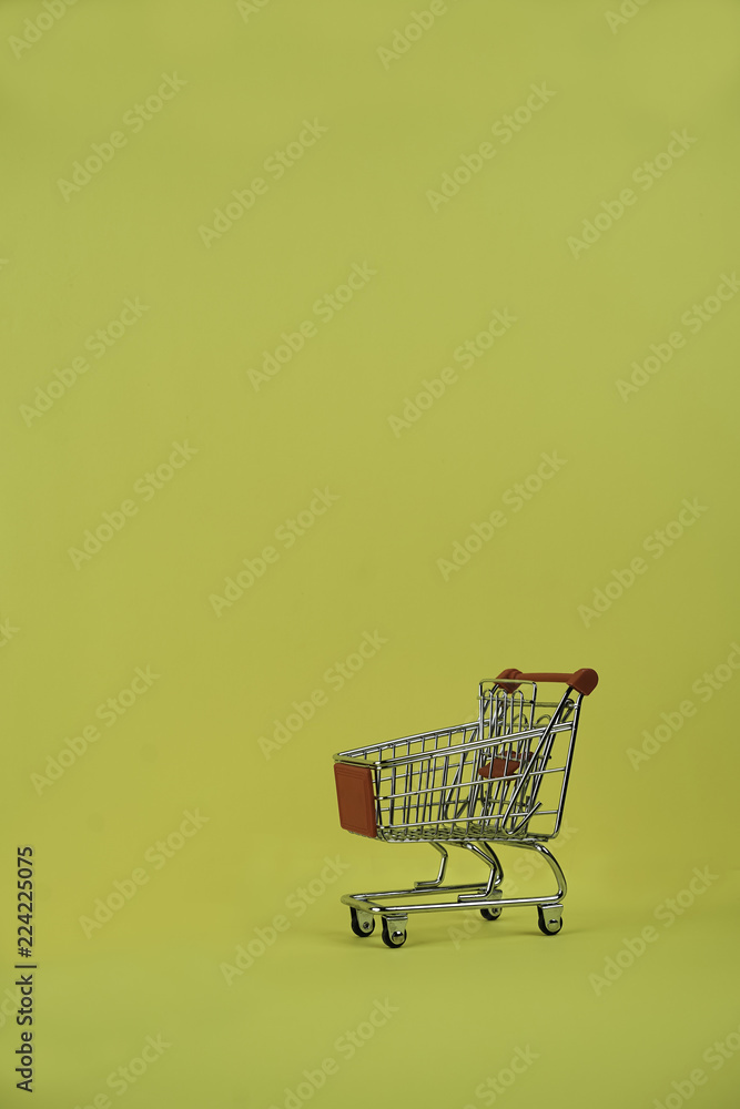 Close-up shopping cart or shop trolley from supermarket on yellow background, creative concept, copy space. Minimalism style. Sale, Black Friday, discount.