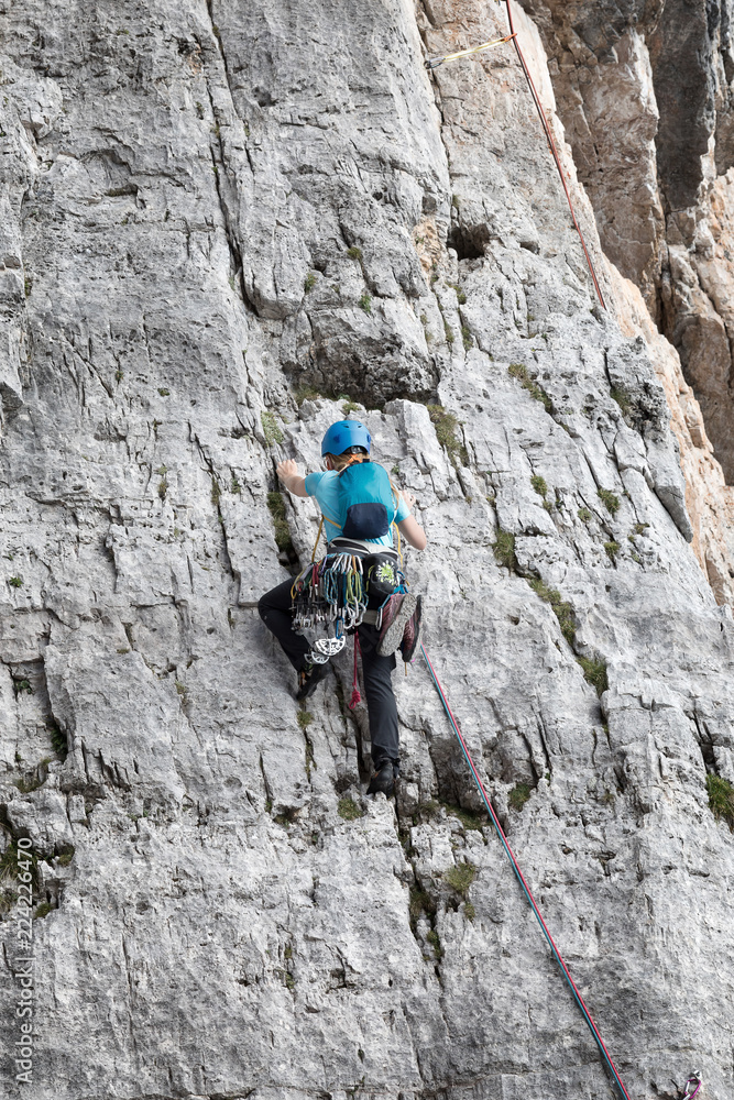A female climber climbs alone on top of a rocky wall