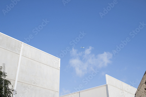 Industrial building and an airplane on the blue sky.