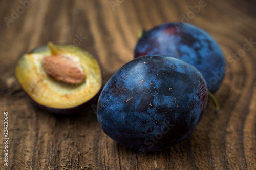 Fresh blue plums on wood table background. Sweet autumn fruit. Delicious and healthy raw food full of vitamins.