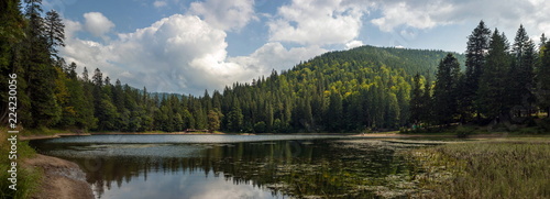 Beautiful views of the mountain lake and the mountains covered with forest in the summer. Popular tourist attraction. Fantastic landscape of Lake Sinevir in the Carpathians, Ukraine. photo