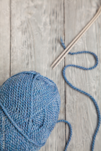 blue ball of yarn with spokes on grey wooden background