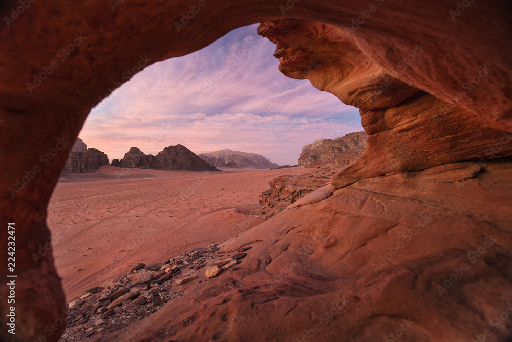 view from natural cave to pink sky in sunset in desert