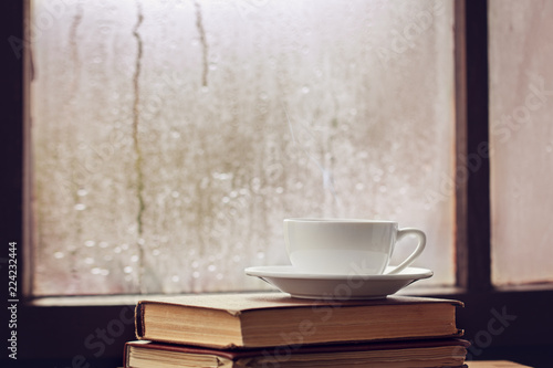 Фотография Cup of autumn tea (coffee, chocolate) and yellow leaves on rainy window, copy space