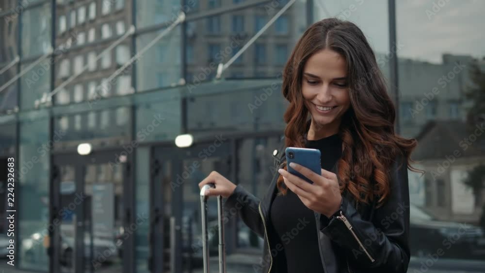 Portrait of a girl using the voice recognition of the phone and looking at cell phone near airport terminal in hotel on vacation tourist speech personal assistant natural language user interface audio Portrait of a girl using the voice recognition of the phone and looking at cell phone near airport terminal in hotel on vacation tourist speech personal assistant natural language user interface audio
