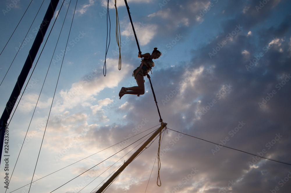 silhouette of a young girl jumping on a bungee on a trampoline on a sunset background on a sea silhouette of a young girl jumping on a bungee on a trampoline on a sunset background on a sea