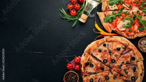 A set of pizza. On a black wooden background. Free space for text. Top view.