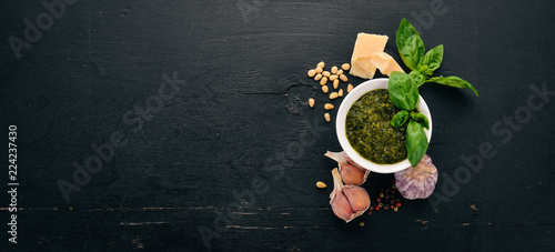 Preparing basil pesto sauce. Basil, parmesan cheese, olive oil. Top view. On a black wooden background. Free space for text.