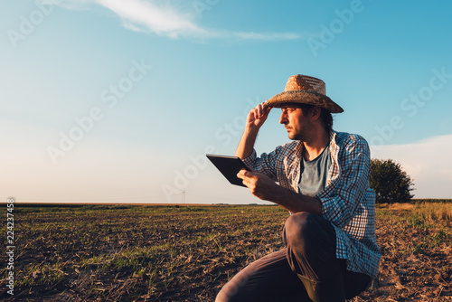 Farmer agronomist with tablet computer in bare empty field