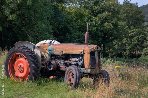 Old, rusty and abandoned tractor in field on a sunny evening