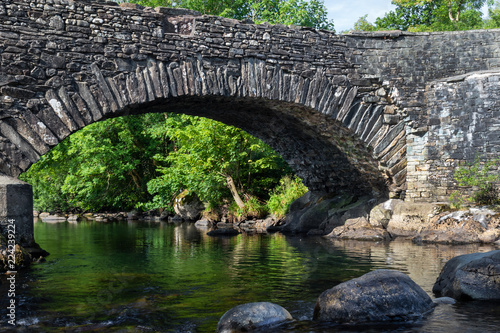 Old stone bridge over River Duddon in Ulpha in the Lake District National Park, UK. Scenic view of English countryside on a sunny day photo