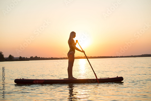 Young sexy woman swimming on stand up paddle board.Water sports , active lifestyle.	