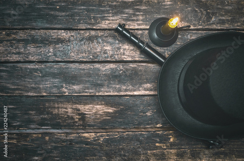 Musket gun, bowler hat and burning candle on wooden table background. Duel. photo