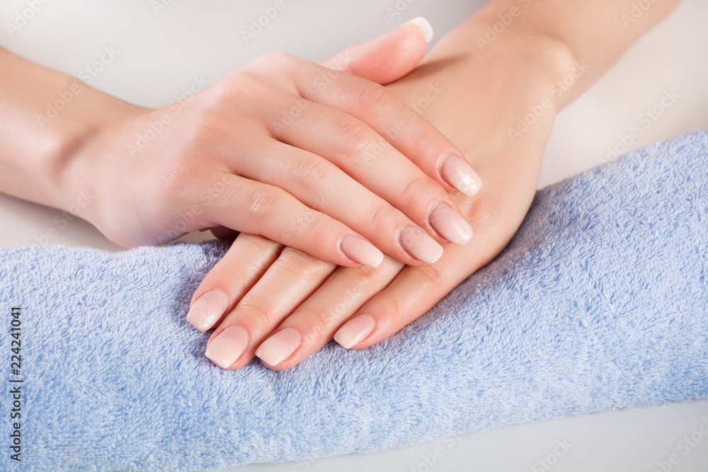 Fototapeta premium Ombre french nails on woman hands on blue gently towel in beauty salon. Manicure and beauty concept