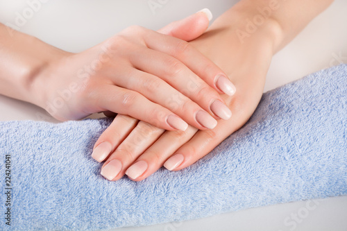 Ombre french nails on woman hands on blue gently towel in beauty salon. Manicure and beauty concept