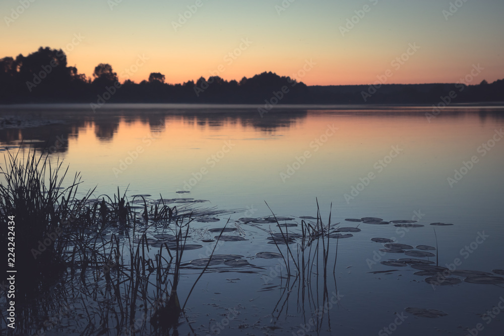 Twilight dark lake rustic countryside tranquil scenery landscape sunset with pink sky and tranquil water mirror reflections in vintage style