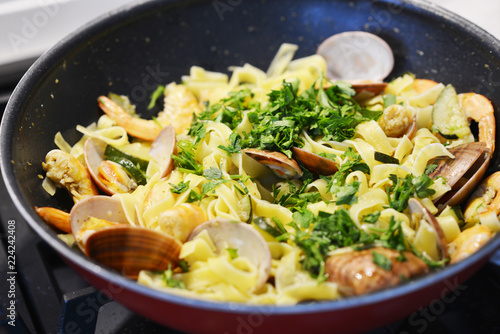 Appetizing seafood pasta with vongole and fried  shrimps in a pan

